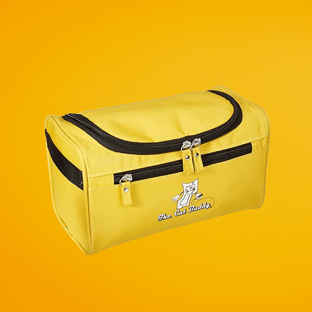 A closed, compact yellow travel grooming kit bag with black zippers and The Cut Buddy logo, designed for portable storage of hair and beard tools.