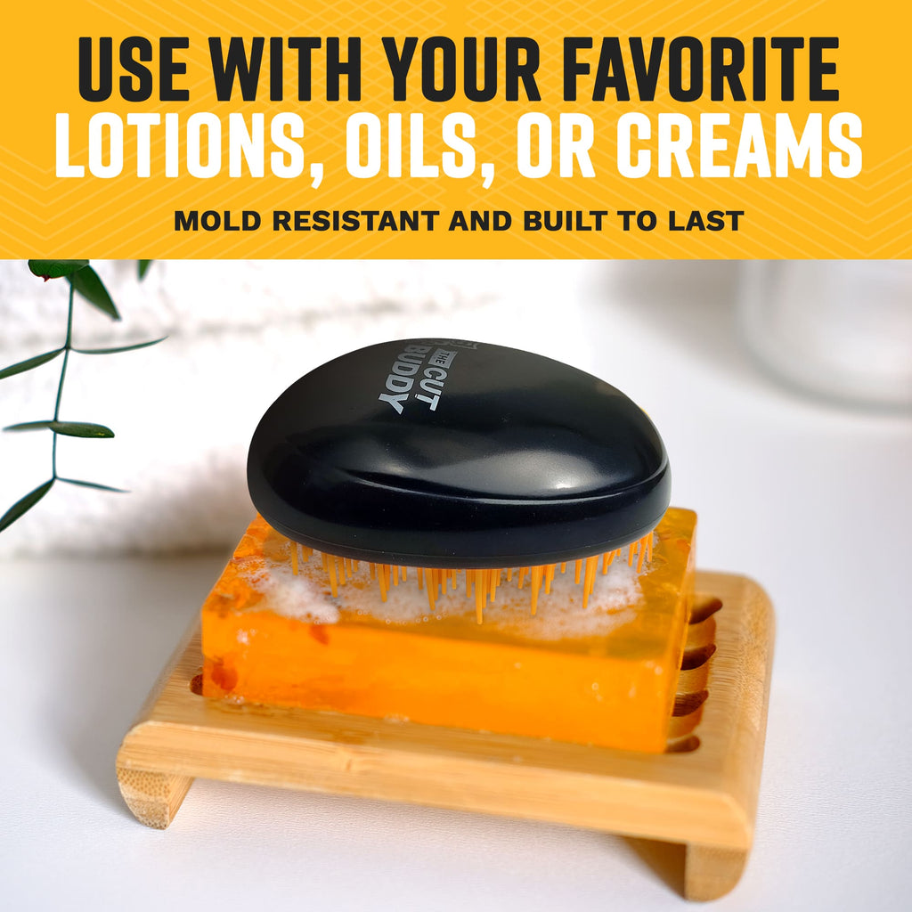 A person holding an orange and black palm-held detangling brush, demonstrating the ergonomic grip and compact size against a yellow background.