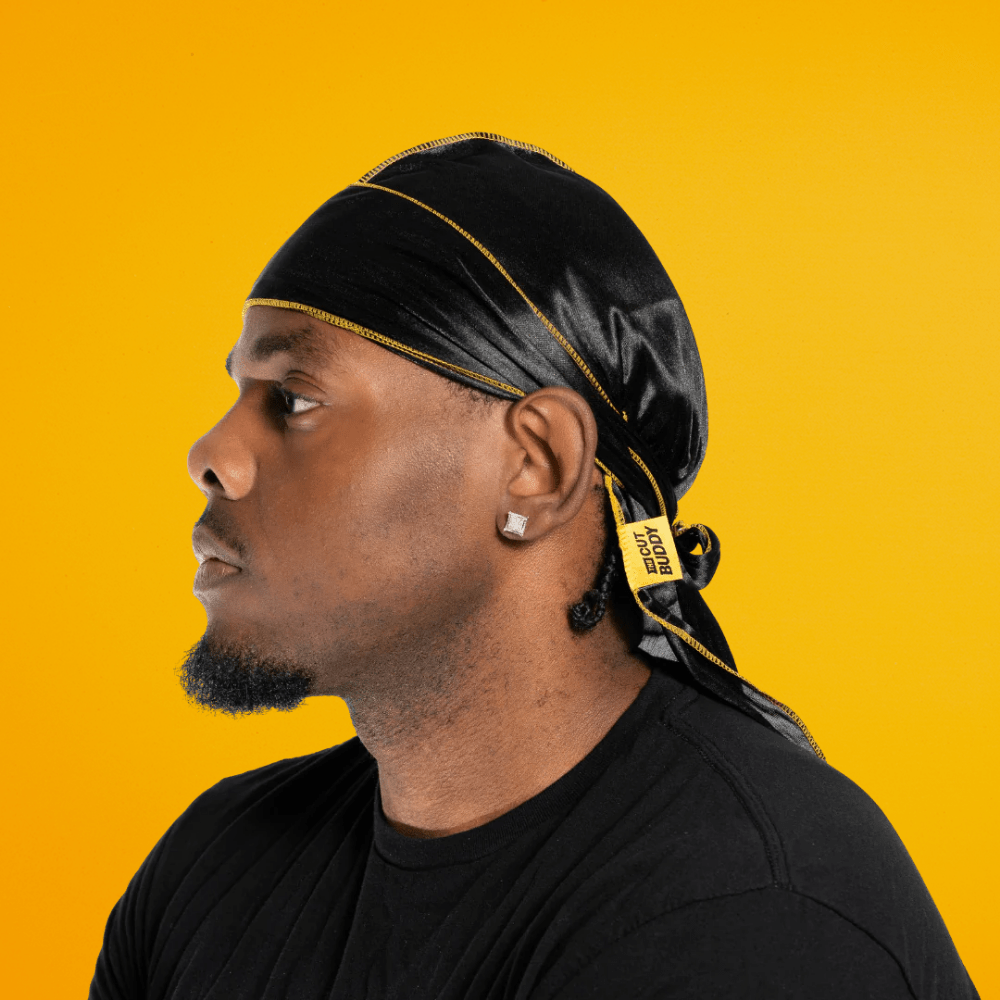 Side profile view showing the fit and compression of The Cut Buddy black silky durag with gold-yellow outer stitching for 360 waves.