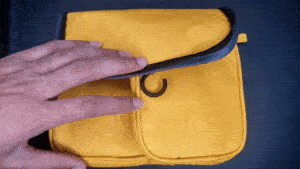 A person demonstrating the internal elastic loops and storage compartments of a yellow travel grooming case.