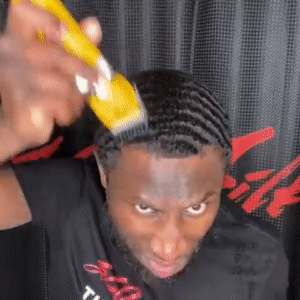 A man using a yellow professional clipper from The Cut Buddy to create a precise lineup on short hair with a 360-wave pattern.